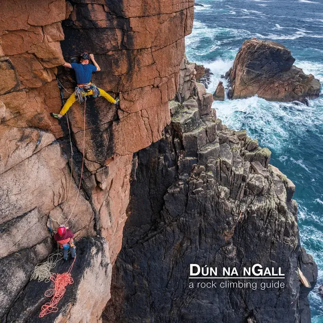 Two mountain climbers climbing a cliff in County Donegal, Ireland.